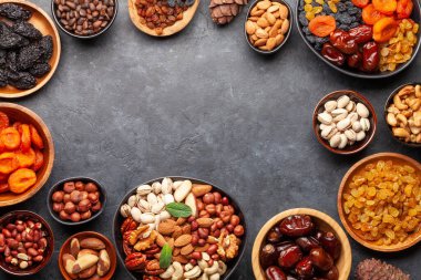 Koyu taş bir masada çeşitli kurutulmuş meyve ve fındıklar. Üst görünüm düzlüğü kopyalama alanı ile yatıyordu