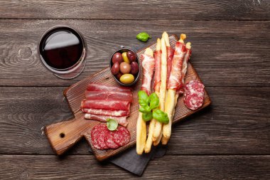 Et ve zeytinli antipasto. Aperatif seçme tahtası ve kırmızı şaraplı bardak. Üst Manzara. Düz yatıyordu