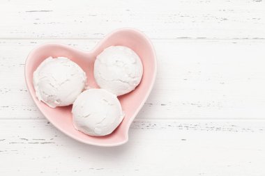 Vanilyalı dondurma kepçeleri ahşap arka planda kalp şeklinde kâsede. Kopyalama alanı olan üst görünüm. Düz yatıyordu