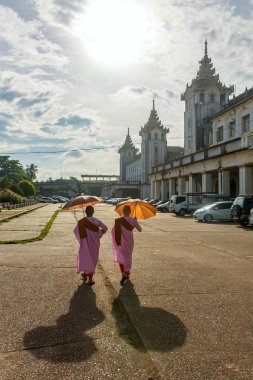 Yangon, Myanmar - September 29, 2016: Yangon street scene: Buddhist nuns walk near by Yangon central railway station in Burma. clipart