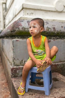 Yangon, Myanmar - September 26, 2016: Portrait of an unidentified burmese kid with traditional tanaka on the face. clipart