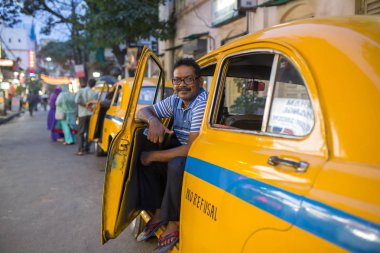 Kolkata, Hindistan - 5 Nisan 2017: Bir Hintli taksi sürücüsü Kolkata sokaklarında onun antika oldtimer sarı taksi ile portresi