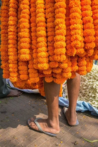 Indian salesman covered with marigold flowers garland on the flower market in Kolkata, India