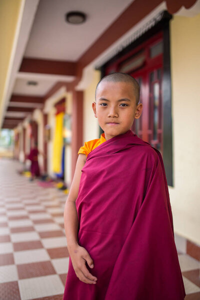 Gangtok, India - May 3, 2017: Unidentified young novice buddhist monk in traditional red robes standing in front of Tsuglakhang monastery in Gangtok, Sikkim, India