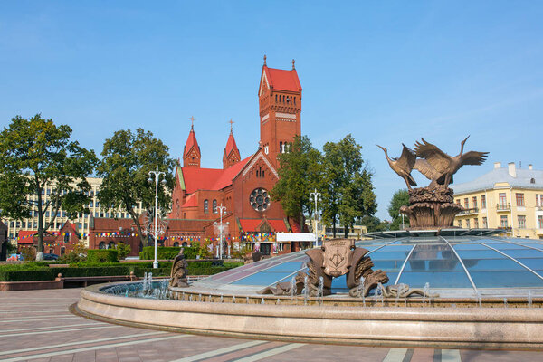 Church Of Saints Simon also known as the Red Church and fountain with name of belarusian city Brest on it at Independence Square In Minsk, Belarus.