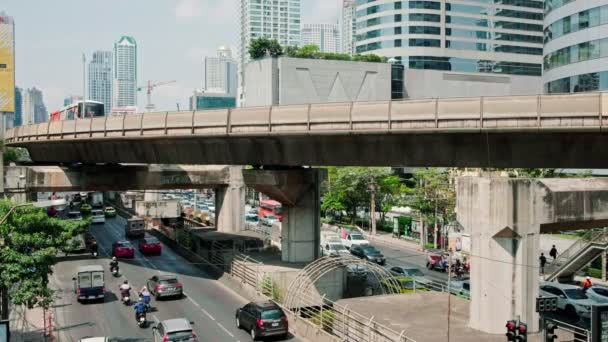 Bts skytrain fährt über die vielbefahrene straße in bangkok, thailand — Stockvideo