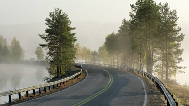 Fiński krajobraz z wąską drogą samochodową przechodzącą przez jezioro. — Wideo stockowe