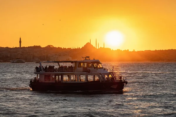 Kapal feri penumpang dan masjid siluet saat matahari terbenam di Istanbul, Turki — Stok Foto