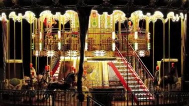 Geceleyin bir lunaparkta aydınlatılmış klasik çocuk atlıkarıncaları.