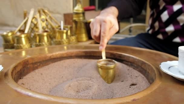 Close-up handen van een man koken turkse koffie op warm zand — Stockvideo