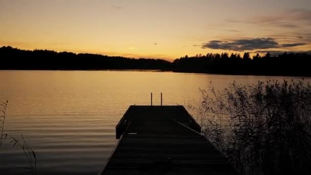 Пов рухається на самоті з маленьким дерев'яним причалом на спокійному озері під час сутінок у Фінляндії. — стокове відео