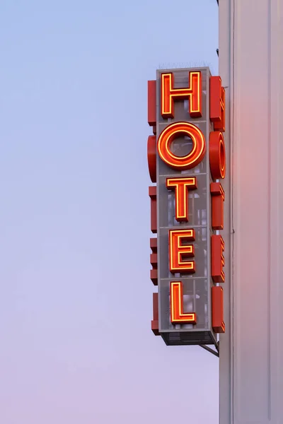 Neon hotel sign on the building corner against the sunset sky — Stock Photo, Image