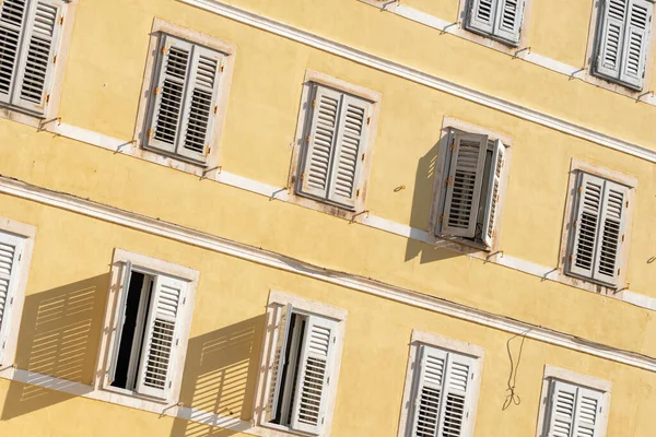 Sarı duvarda beyaz kepenkleri olan geleneksel Akdeniz tarzı bina