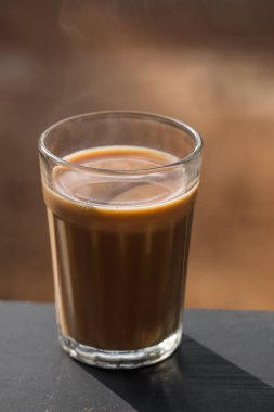 Ahşap bir tahtanın üzerinde cam bir Hint masala çayı.