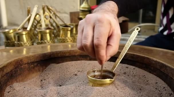 Närbild händer en man matlagning turkiskt kaffe på varm sand — Stockvideo