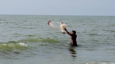 Kimliği belirlenemeyen Hintli balıkçı, Kerala State, Hindistan 'da ağ atarak balık yakalıyor.