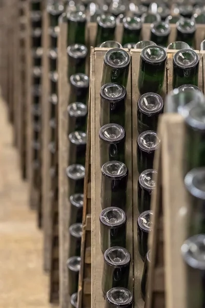 Μπουκαλάκια αφρώδους οίνου στοιβαγμένα σε παλιό κελάρι κοντά στο παρασκήνιο. — Φωτογραφία Αρχείου