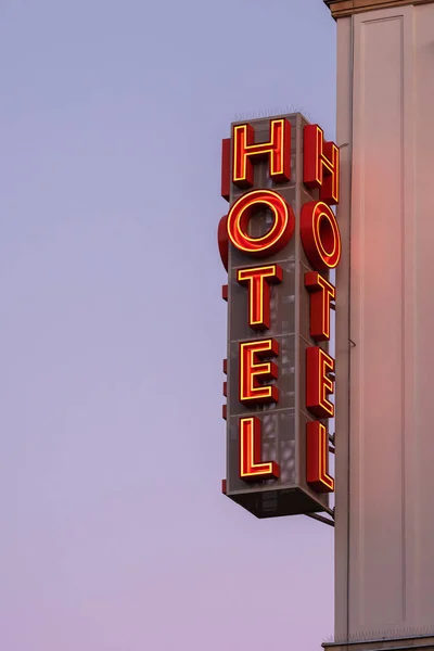 Neonový hotelový nápis na rohu budovy proti západu slunce — Stock fotografie