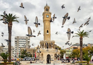 Flock of pigeons flying around the Izmir Clock Tower in Izmir, Turkey. clipart