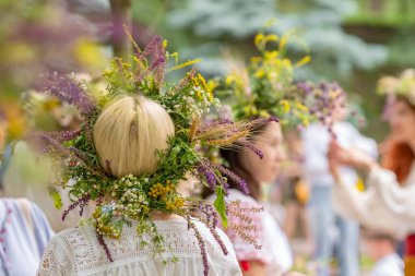 Unidentified women in traditional dresses with summer solstice wreaths made from field flowers, grasses and cereals. clipart