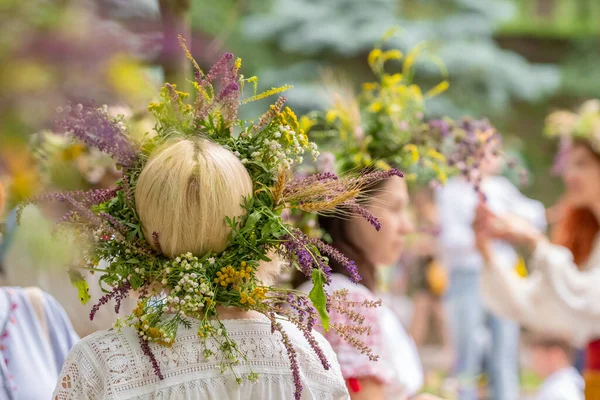 Tunnistamattomat naiset perinteisissä mekoissa, joiden kesäpäivänseisaukset on tehty pellon kukista, ruohosta ja viljasta. — kuvapankkivalokuva