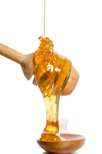 Honig tropft aus einem hölzernen Honigwagen isoliert auf weißem Rücken lizenzfreie Stockbilder