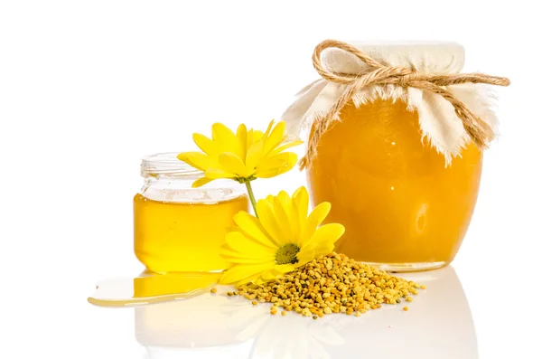 The jar of honey near a pile of pollen and flower isolated on wh — Stock Photo, Image