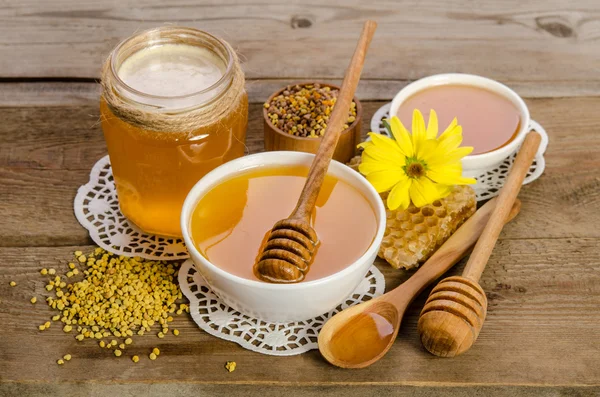 Produits d'abeilles (miel, pollen, rayons de miel) sur fond de bois — Photo