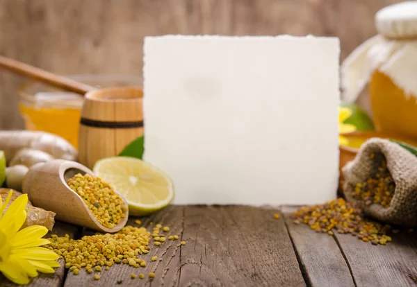 Соты, мед, имбирь, пыльца, лимон на деревянном столе с — стоковое фото
