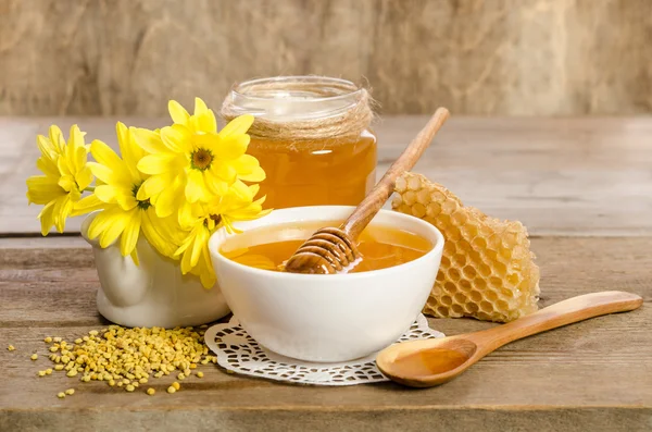 Yellow flowers and bee products (honey, pollen, honeycombs) on w — Stock Photo, Image