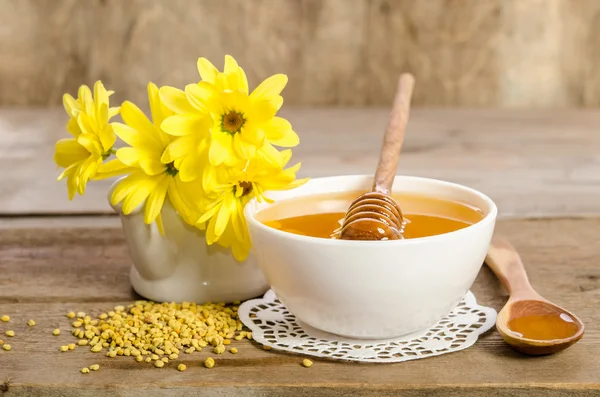 Žluté květy a včelí produkty (med, pyl) na dřevěné pozadí — Stock fotografie