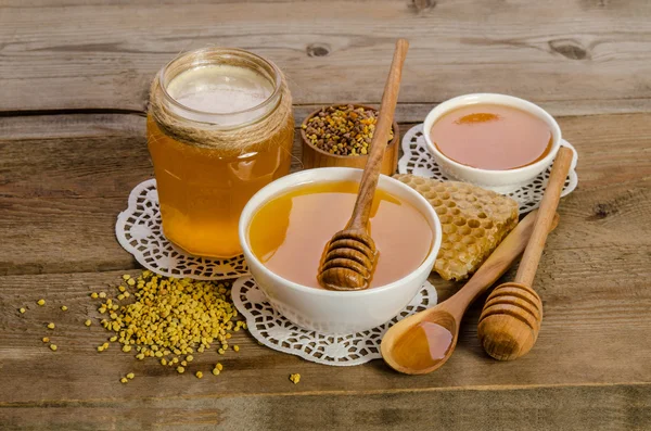 Produtos apícolas (mel, pólen, favos de mel) sobre fundo de madeira — Fotografia de Stock