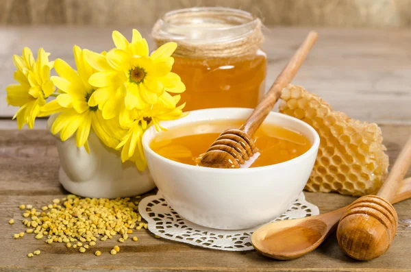 Yellow flowers and bee products (honey, pollen, honeycombs) on w — Stock Photo, Image