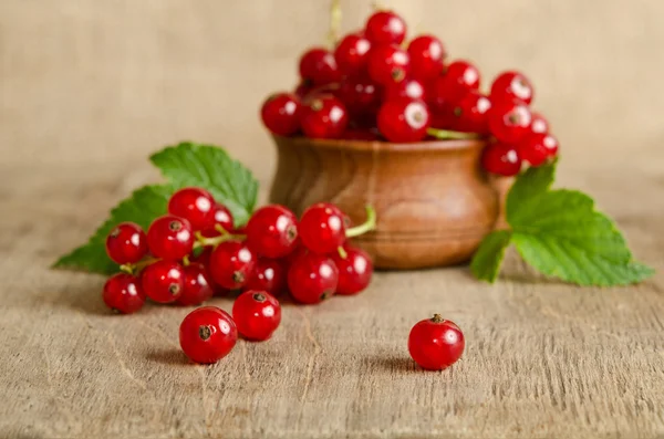 Grosella roja en plato de madera sobre la mesa — Foto de Stock