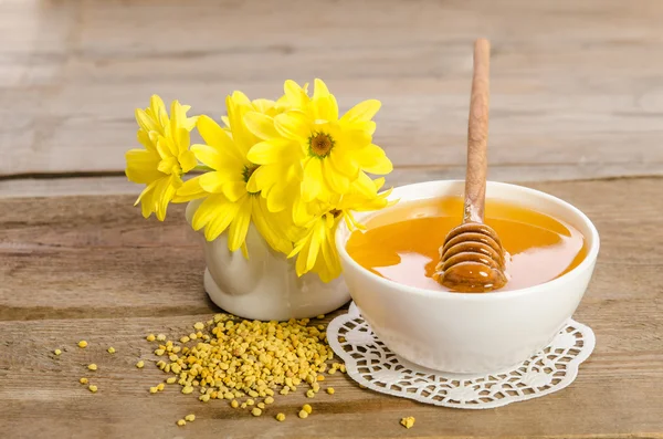 Flores amarelas e produtos de abelha (mel, pólen) em backgr de madeira — Fotografia de Stock