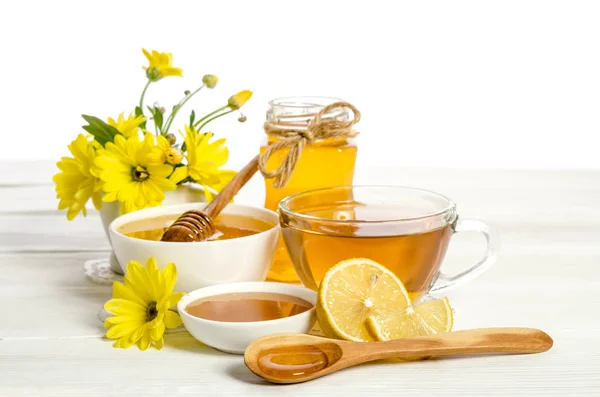 Gula blommor, te, citron och honung på träbord — Stockfoto