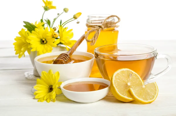 Gula blommor, te, citron och honung på träbord — Stockfoto