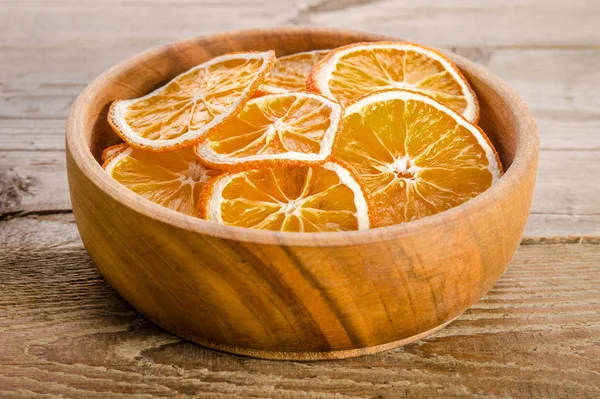 Wooden bowl with dry orange on wooden table — Stock Photo, Image