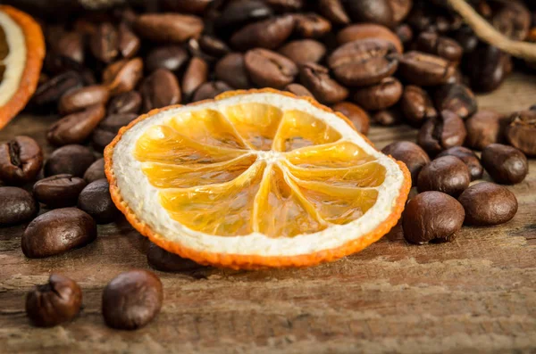 Coffee beans and dry slice of orange on wooden table. — Stock Photo, Image