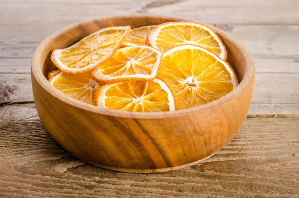Wooden bowl with dry orange on wooden table — Stock Photo, Image