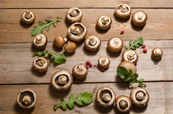 Frische Pilze mit Rucolablättern auf Holzgrund — Stockfoto