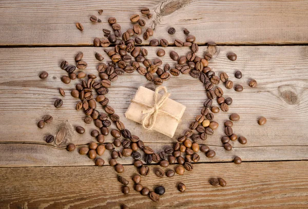 Marco-corazón de granos de café y pequeño paquete dentro de ella — Foto de Stock