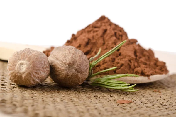 Nutmegs with a sprig of rosemary and cacao powder — Stock Photo, Image