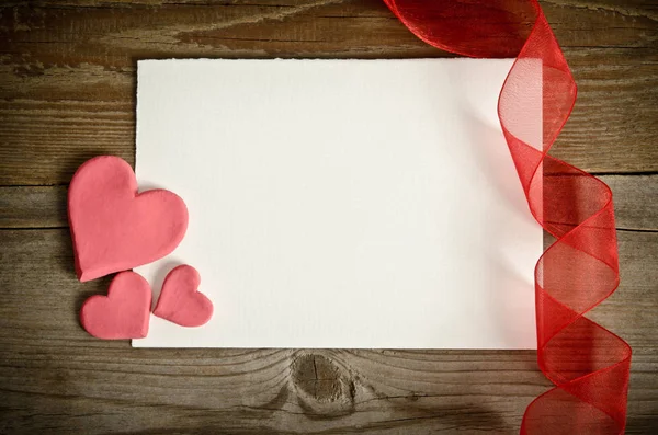 Piece of paper lying with hearts and ribbon — Stock Photo, Image