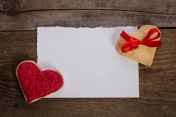 Cookies-corações com cartão vazio na mesa de madeira — Fotografia de Stock