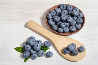 tahta kaşık beyaz tablo içinde yaban mersini