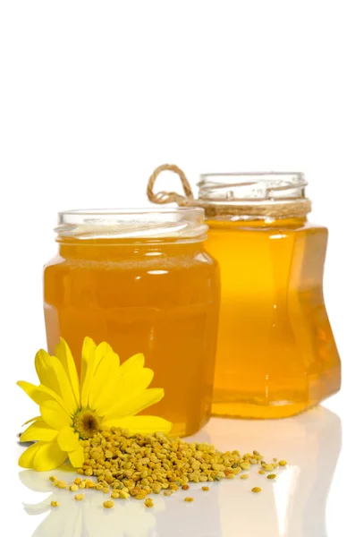 The jars of honey near a pile of pollen and flower isolated on w — Stock Photo, Image
