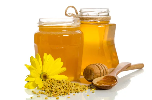 The jars of honey near a pile of pollen and flower isolated on w — Stock Photo, Image