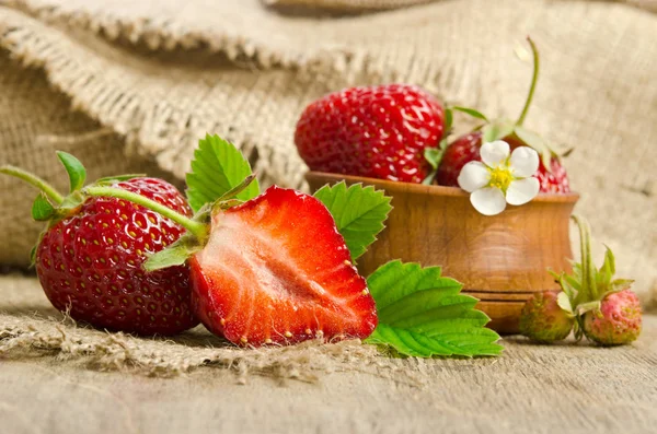 在一个木碗粗麻布背景上的熟草莓 — 图库照片