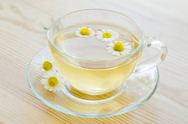 Ahşap masa üzerinde tıbbi papatya çayı fincan